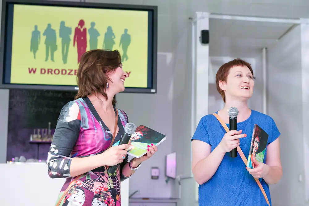 Two women are standing together with microphones in their hands