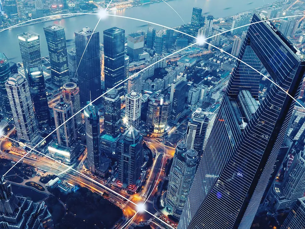 Bird´s eye view of Shangai´s skyscrapers. Several cruved white lines intersect each other above the city, representing connectivity.